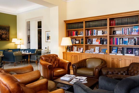 Salone interno del club con poltrone in pelle, librerie e luce calda a Santa Croce Camerina